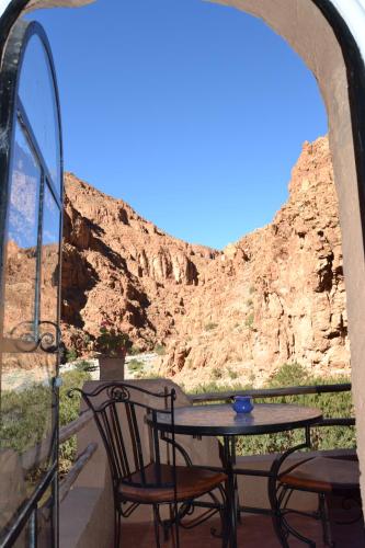 a table and chairs on a balcony with a view of a canyon at Auberge Tissadrine in Akhendachou nʼAït Ouffi