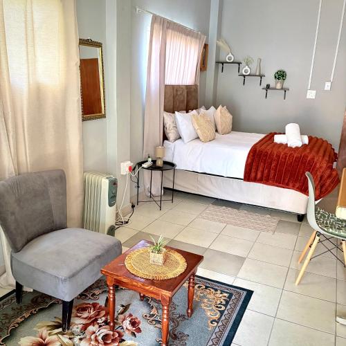 a bedroom with a bed and a chair and a table at The Nest- on Knowling Street in Grahamstown