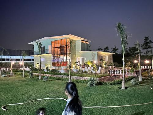 a woman walking in front of a house at night at Singhal's Farm House in Greater Noida