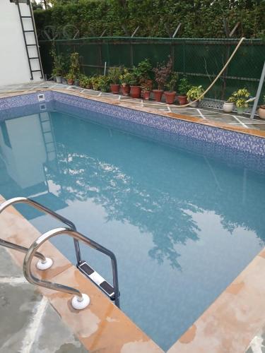 a swimming pool with a hand rail in the water at Singhal's Farm House in Greater Noida