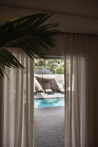 a view of a pool through a window with curtains at âmé by NOAH in Cape Town