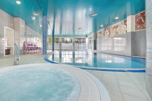 a large pool with a hot tub in a building at Chimera Spa Niechorze in Niechorze