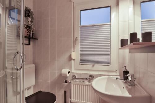 a bathroom with a sink and a toilet and a window at Bungalow Paul in Nienhagen