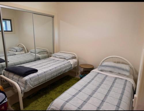a room with two beds and a mirror at Executive Accommodation Bairnsdale in Bairnsdale