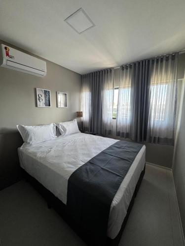 a bedroom with a large bed in front of windows at Apartamento Ipioca Beach Life - Maceió in Maceió