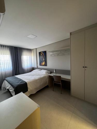 a bedroom with a bed and a desk and a table at Apartamento Ipioca Beach Life - Maceió in Maceió
