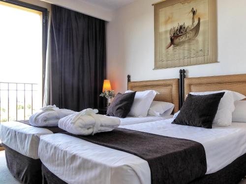 two beds in a hotel room with towels on them at Termes Montbrio Hotel & Spa in Montbrió del Camp