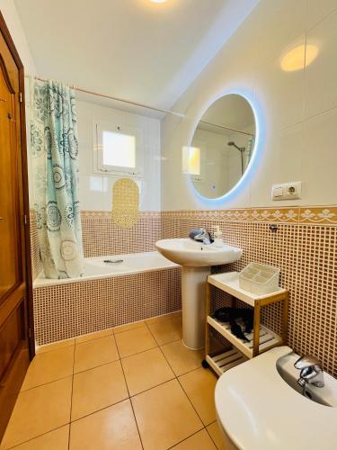 a bathroom with a sink and a mirror and a tub at Costa Norte in Alcalà de Xivert