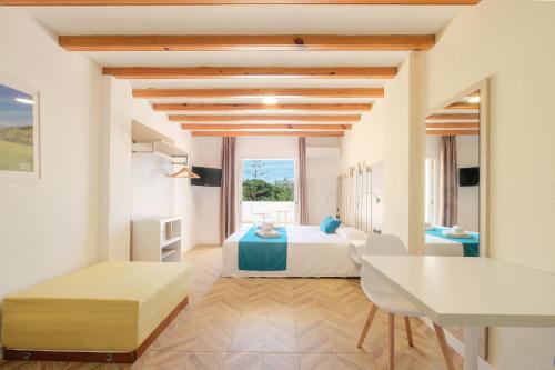 a bedroom with two beds and a desk in a room at azuLine Apartamentos Can Sanso in Santa Eularia des Riu
