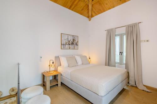 a white bedroom with a bed and a window at Sarakina Urban Grace in Stone by 8essentially in Heraklio