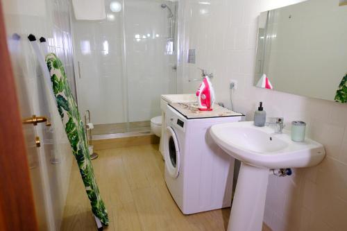 a white bathroom with a sink and a washing machine at Renée Guest House in Paestum