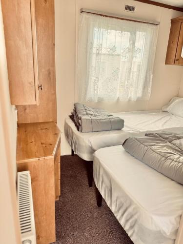 a room with three beds and a window at 6 Birth Cosy caravan 134 Sealands in Ingoldmells
