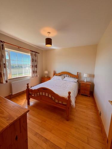a bedroom with a wooden bed and a large window at Beach Side House in Quilty in Quilty