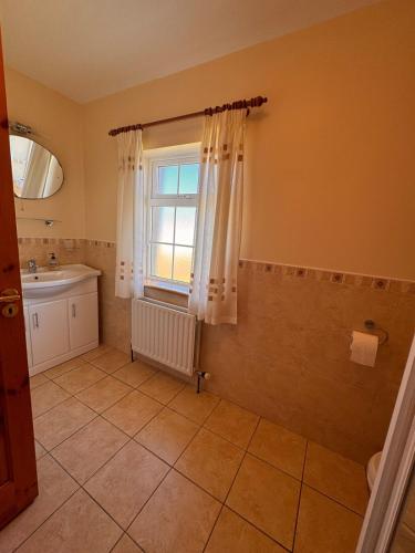 a bathroom with a sink and a window at Beach Side House in Quilty in Quilty