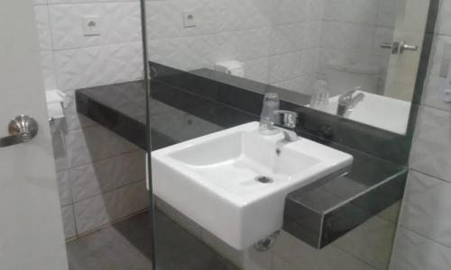 a bathroom with a white sink and a glass shower at Hotel Ella Tambolaka in Tambolaka Airport