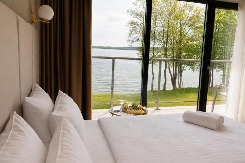 a bedroom with a bed with a view of the water at Blue & Green Masurian Hotel in Węgorzewo