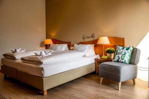 a bedroom with a large bed and a chair at Hotel Stoiser Graz -Parkplatz inbegriffen! in Graz