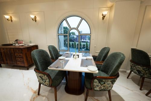 a dining room with a table and green chairs at Shree Anantay Club & Resort in Ujjain