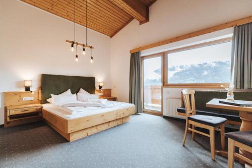 a bedroom with a bed and a desk and a window at Hotel Silberfux in Sankt Veit im Pongau