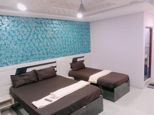 two beds in a room with a painting on the wall at GM Residency in Velankanni