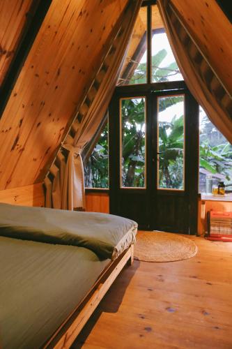 a bedroom with a bed in a room with windows at À La Main Farmhouse in Ấp Trường Sơn
