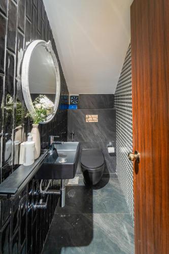 a black bathroom with a sink and a mirror at SaffronStays Forest Edge in Siolim