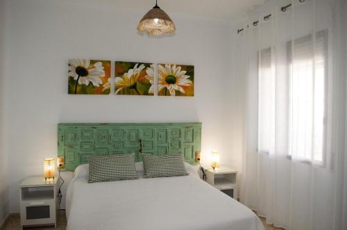a bedroom with a bed with a green headboard and two lamps at Casa Mara in La Herrería