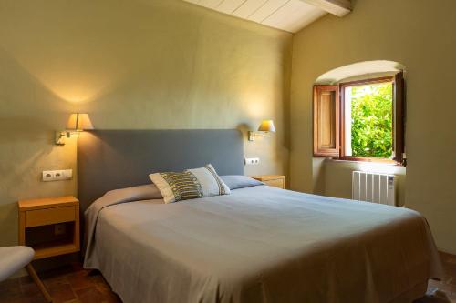 a bedroom with a large bed and a window at Apartamentos en la Rectoria de Regencós in Regencós