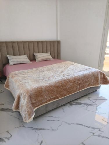 a bed with a brown comforter on the floor at Résidence Harmonia Djerba in Houmt Souk