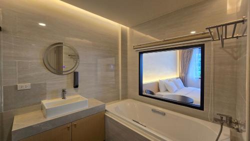 a bathroom with a window with a sink and a bed at Norns Silom Cafe & Stay in Bangkok