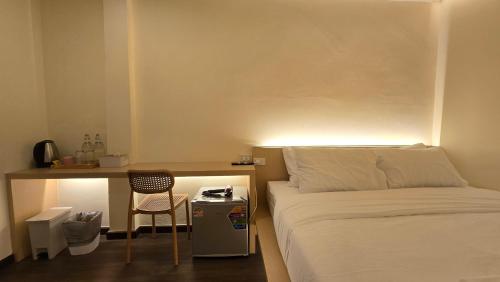 a bedroom with a bed and a desk with a chair at Norns Silom Cafe & Stay in Bangkok