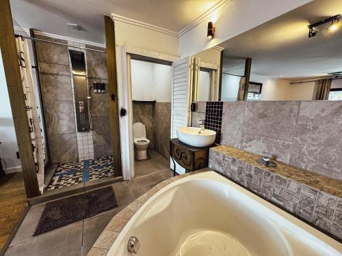 a bathroom with a tub and a shower and a sink at Harties Lake View in Hartbeespoort