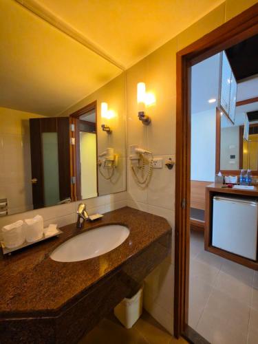 a bathroom with a sink and a large mirror at Dynasty Inn in Bangkok