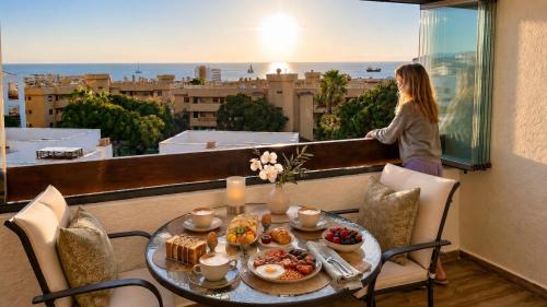 a woman standing on a balcony with a table of food at La Cala Center Premium Penthouse Motorized Terrace & Sea Views in La Cala de Mijas