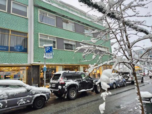 a snow covered street with cars parked in front of a building at LL Properties - H99 Main Street Stay in Akureyri