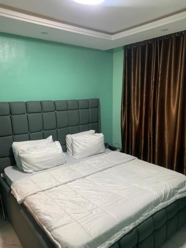 a bedroom with a large bed with a black headboard at Torax Lodge in Ibadan