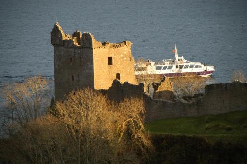 a boat in the water next to a castle at Camping Pod Heaven in Brackla