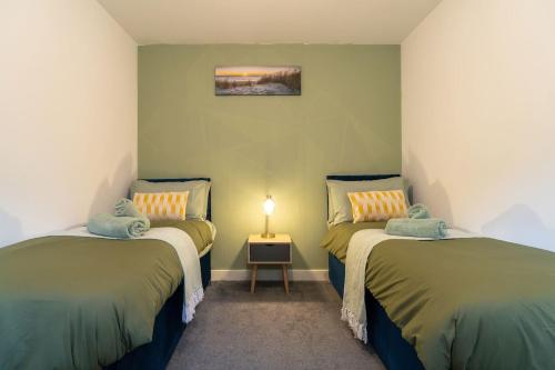 two beds in a room with a lamp on a table at Cozy Urban 2BR with courtyard in Gloucestershire
