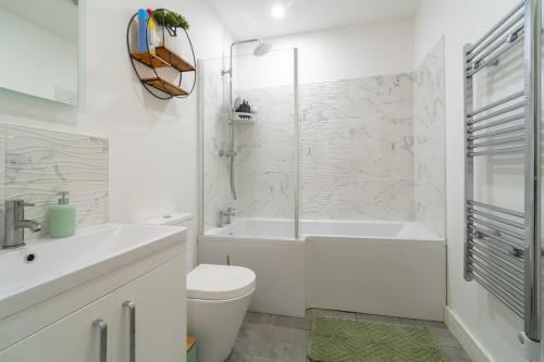 a white bathroom with a tub and a toilet and a sink at Cozy Urban 2BR with courtyard in Gloucestershire