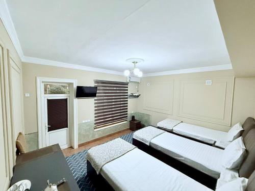 a room with three beds and a table and a window at Shodlik Hostel in Andizhan