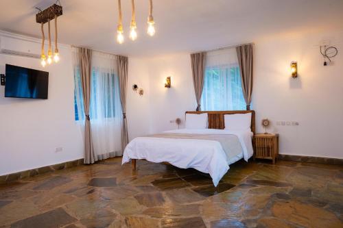 a bedroom with a white bed and two windows at Coast Sun Gardens Cottage Adults Only in Msambweni