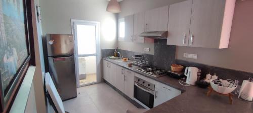 a kitchen with white cabinets and a stainless steel refrigerator at Appartement Résidence fermée avec piscine in Ben Slimane