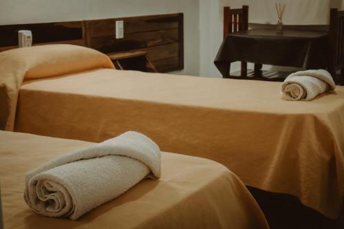 two beds with towels on top of them with a piano at Piedra Alta Hotel & Restaurante in Itá Ibaté
