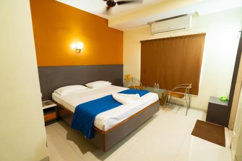 a bedroom with a large bed with a blue blanket at PLA Residency Tanjore in Thanjāvūr