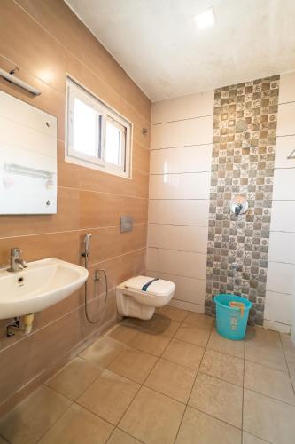 a bathroom with a sink and a toilet and a window at PLA Residency Tanjore in Thanjāvūr