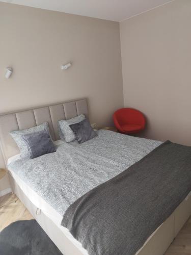 a bedroom with a large bed with a red chair at Apartament Isabell in Busko-Zdrój
