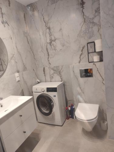 a bathroom with a washing machine and a toilet at Apartament Isabell in Busko-Zdrój