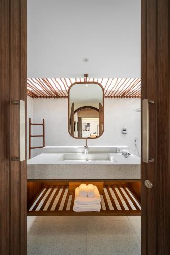 a bathroom with a tub and a sink and a mirror at Solaris Villa Bali in Kuta