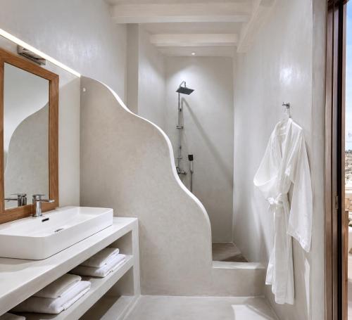 a white bathroom with a sink and a mirror at Crystal Suites in Mikonos