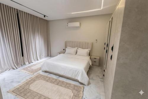 a bedroom with a white bed and a large window at فلة جديدة راقية بمسبح داخلي Luxury villa with indoor pool in Taif